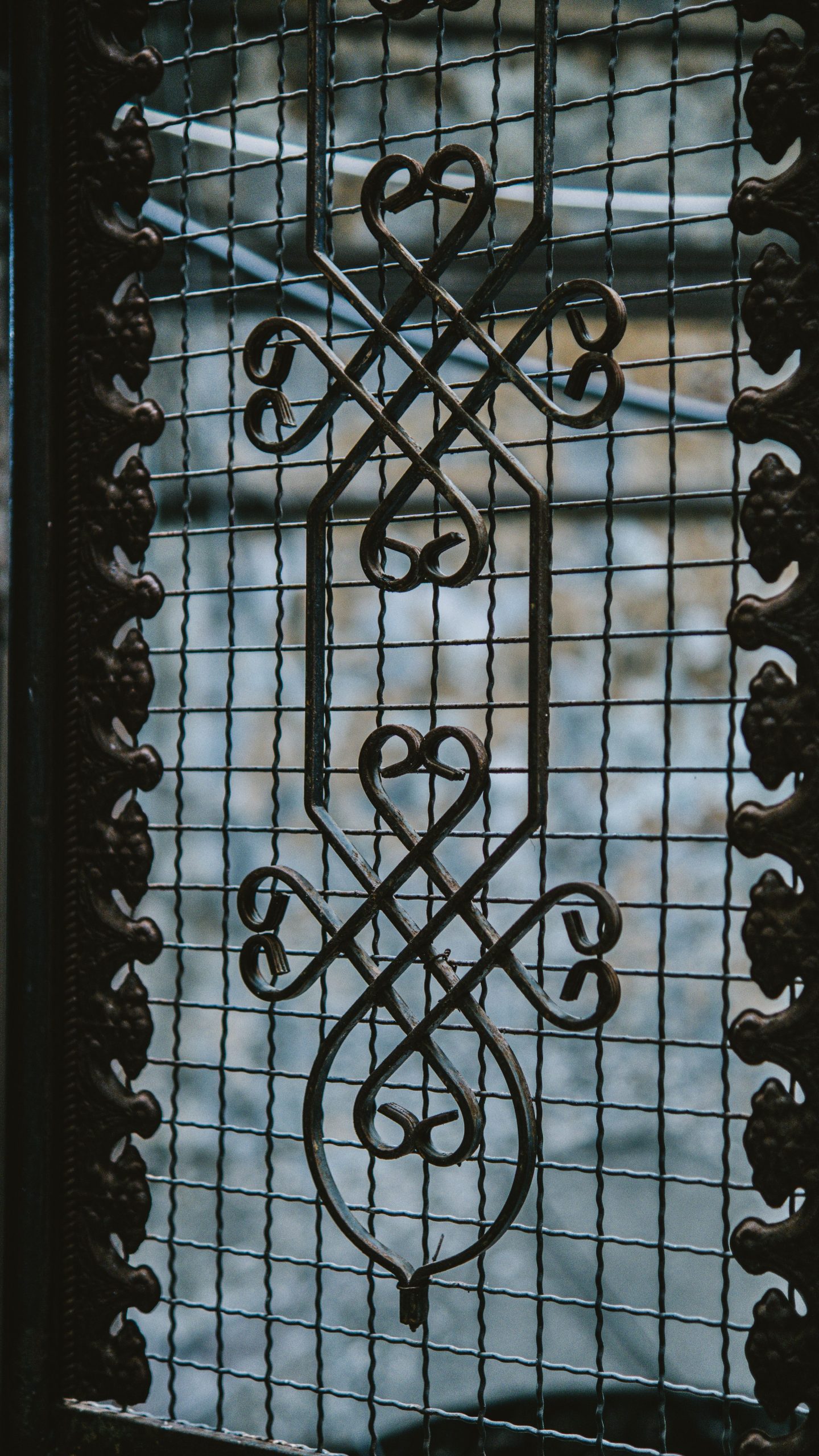 A close-up view of an ornate metal grille with decorative, symmetrical patterns.